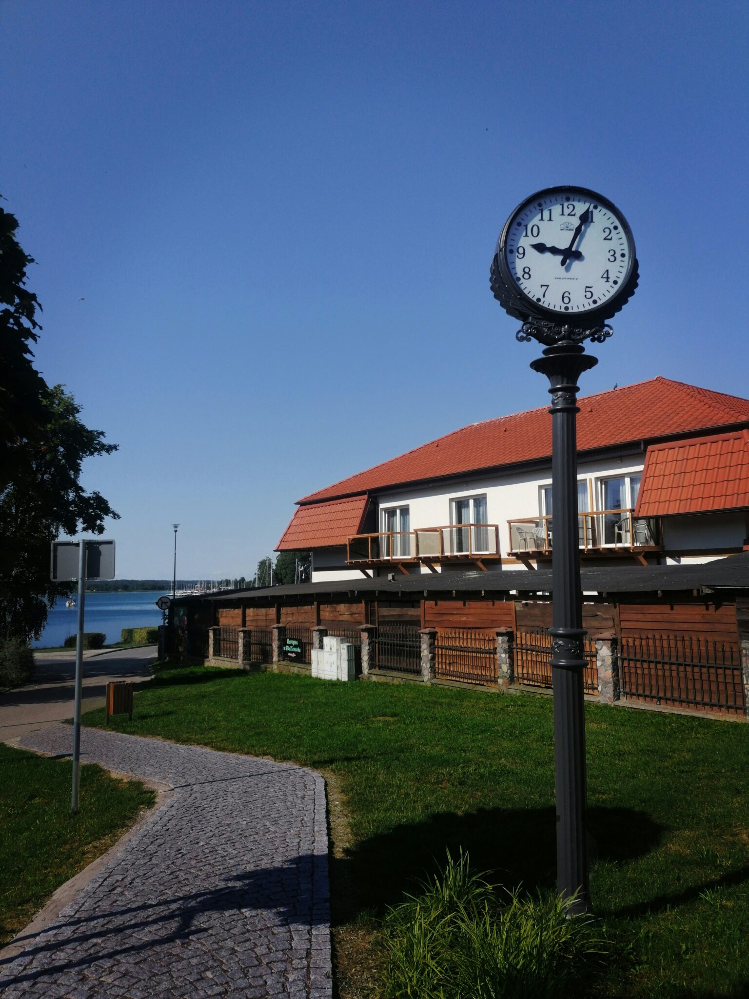 Street clock in Warsaw Poland beside a historic building and quiet city road what time is it in Poland
