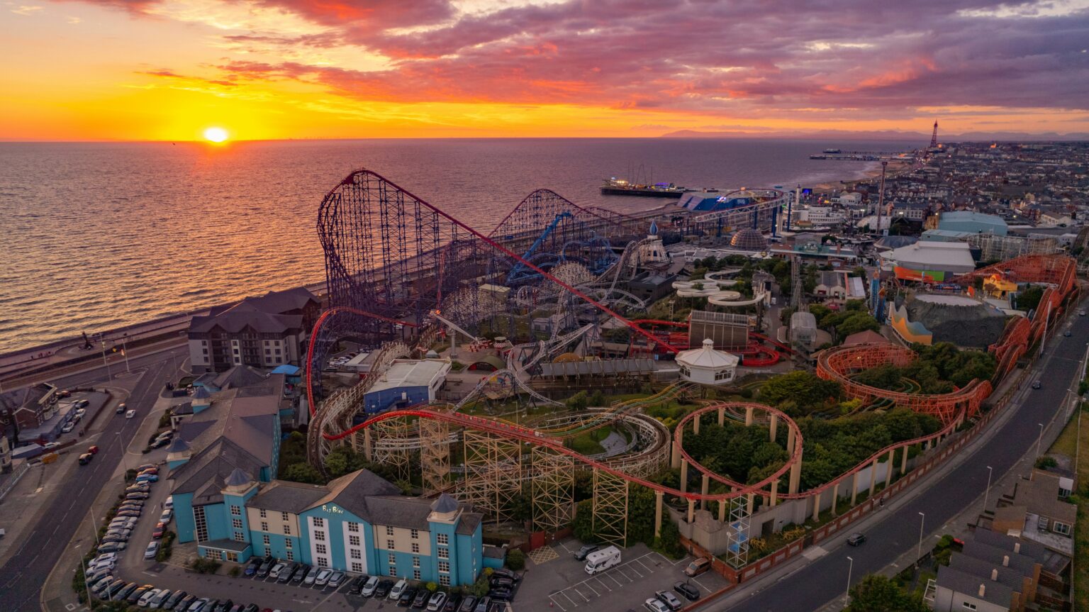 Aerial view of Blackpool Pleasure Beach with roller coasters, the seaside, and a sunset sky best theme parks in England