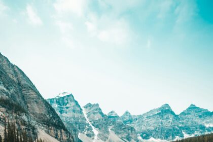 Solo traveler standing on a rock overlooking a turquoise mountain lake.