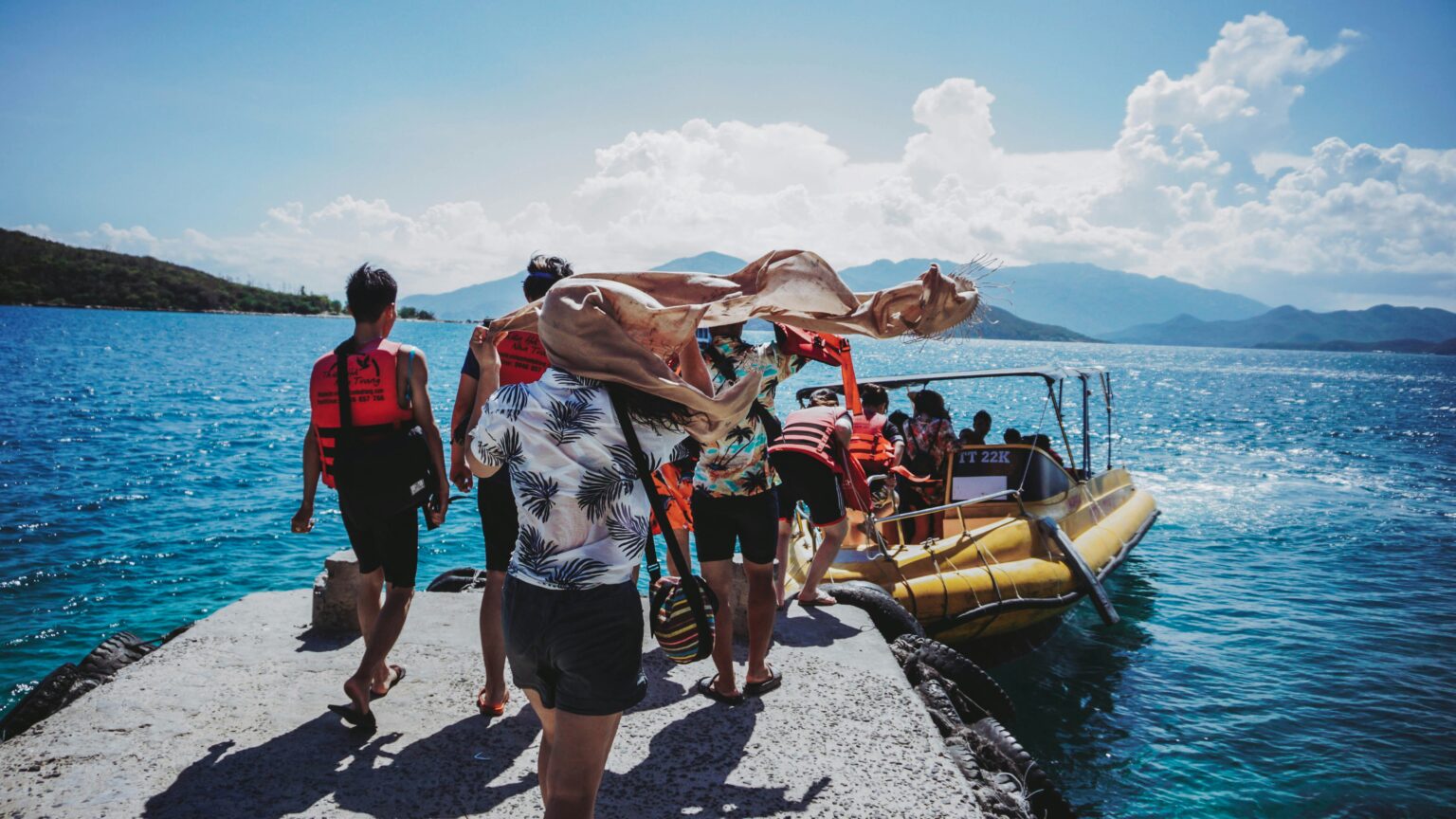Travelers boarding a boat for overseas adventure travel on a tropical blue sea