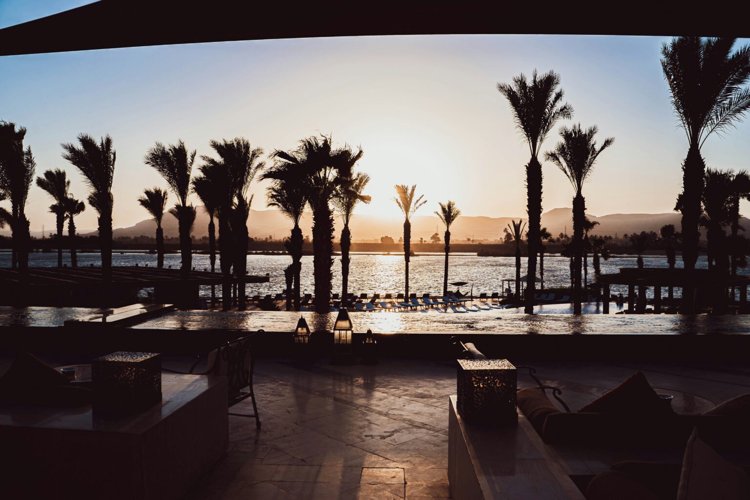 Sunset resort scene with palm trees and water for recommended vacation spots.