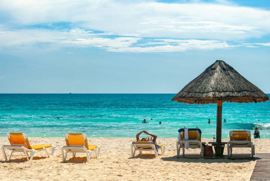 Beach loungers and a palapa umbrella on a white sand Cancun beach, the classic scene of cancun all inclusive travel