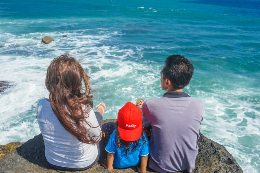 Family Travel Tips showing parents and child enjoying a seaside view together.