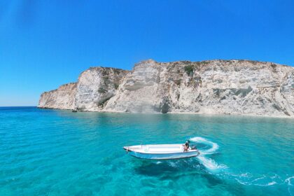 Turquoise sea and white cliffs with a boat, one of the best beaches in Greece.