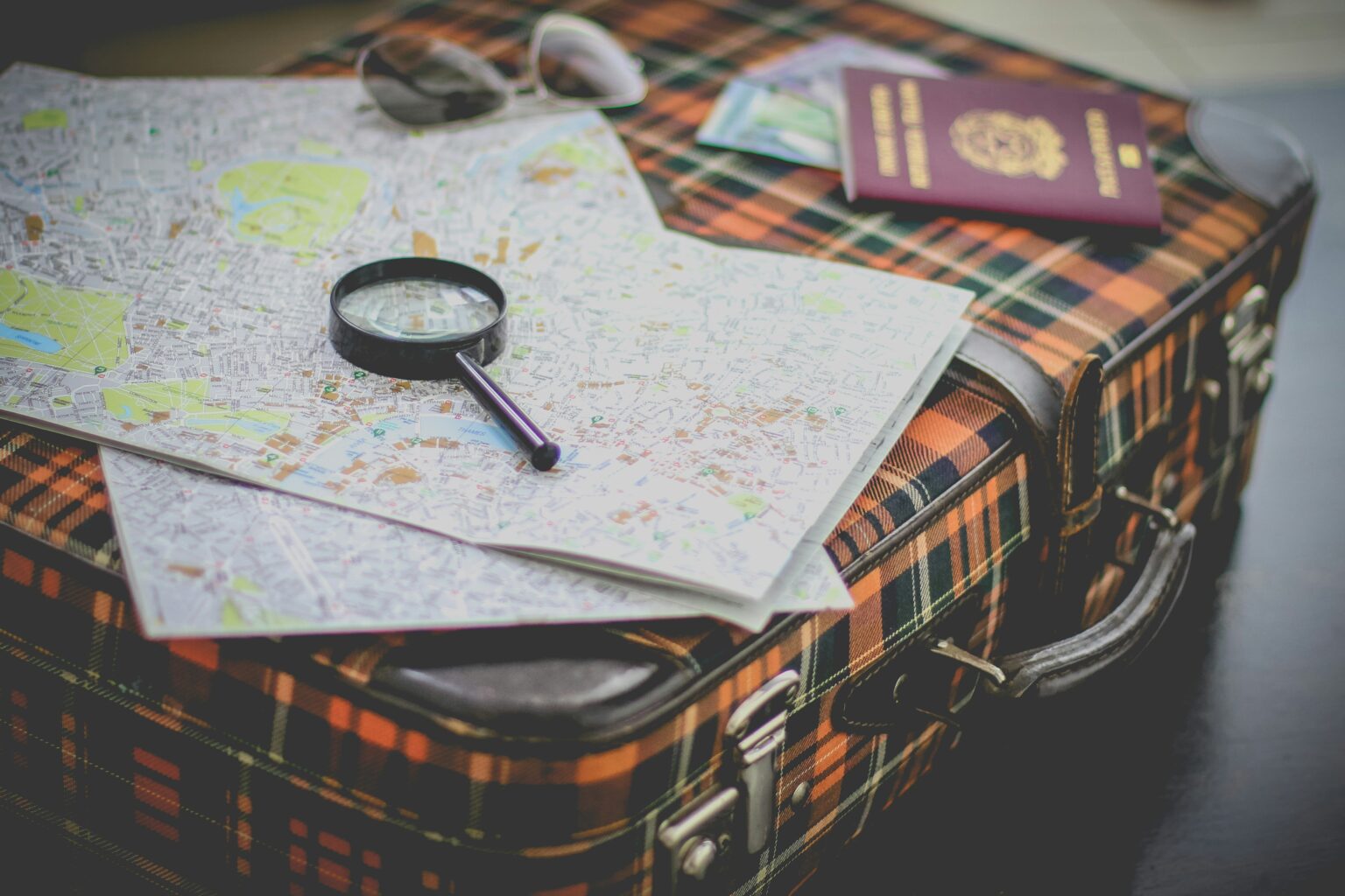 Best places to travel in February shown by a packed suitcase with maps, sunglasses, and a passport
