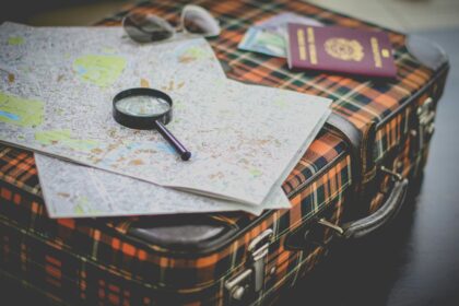 Best places to travel in February shown by a packed suitcase with maps, sunglasses, and a passport