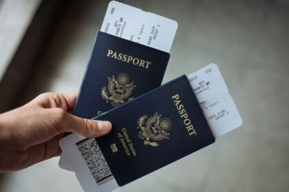 Travel reimbursement for work trips shown by a hand holding two US passports with boarding passes
