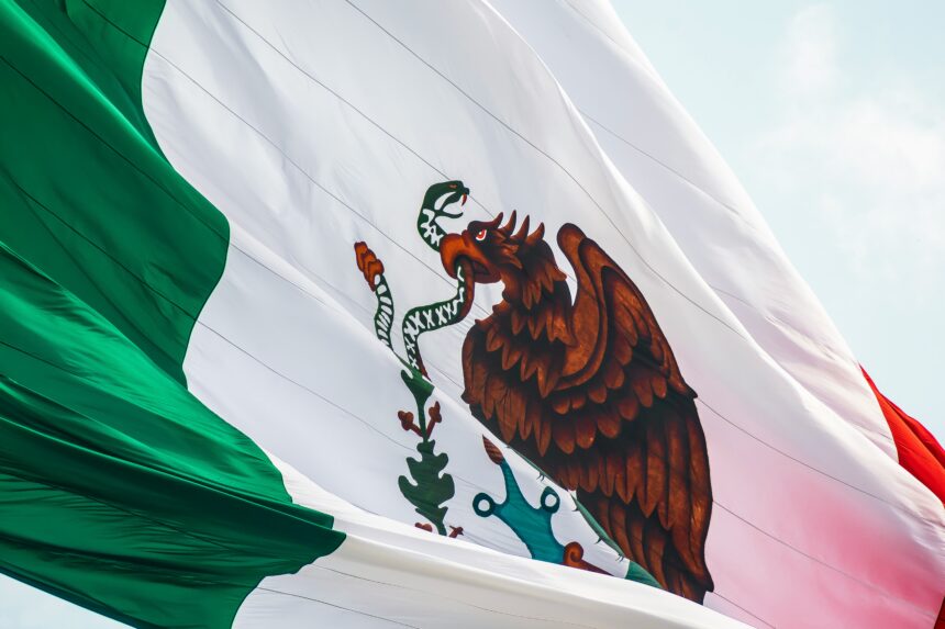 Mexico flag waving in the wind against a bright sky.