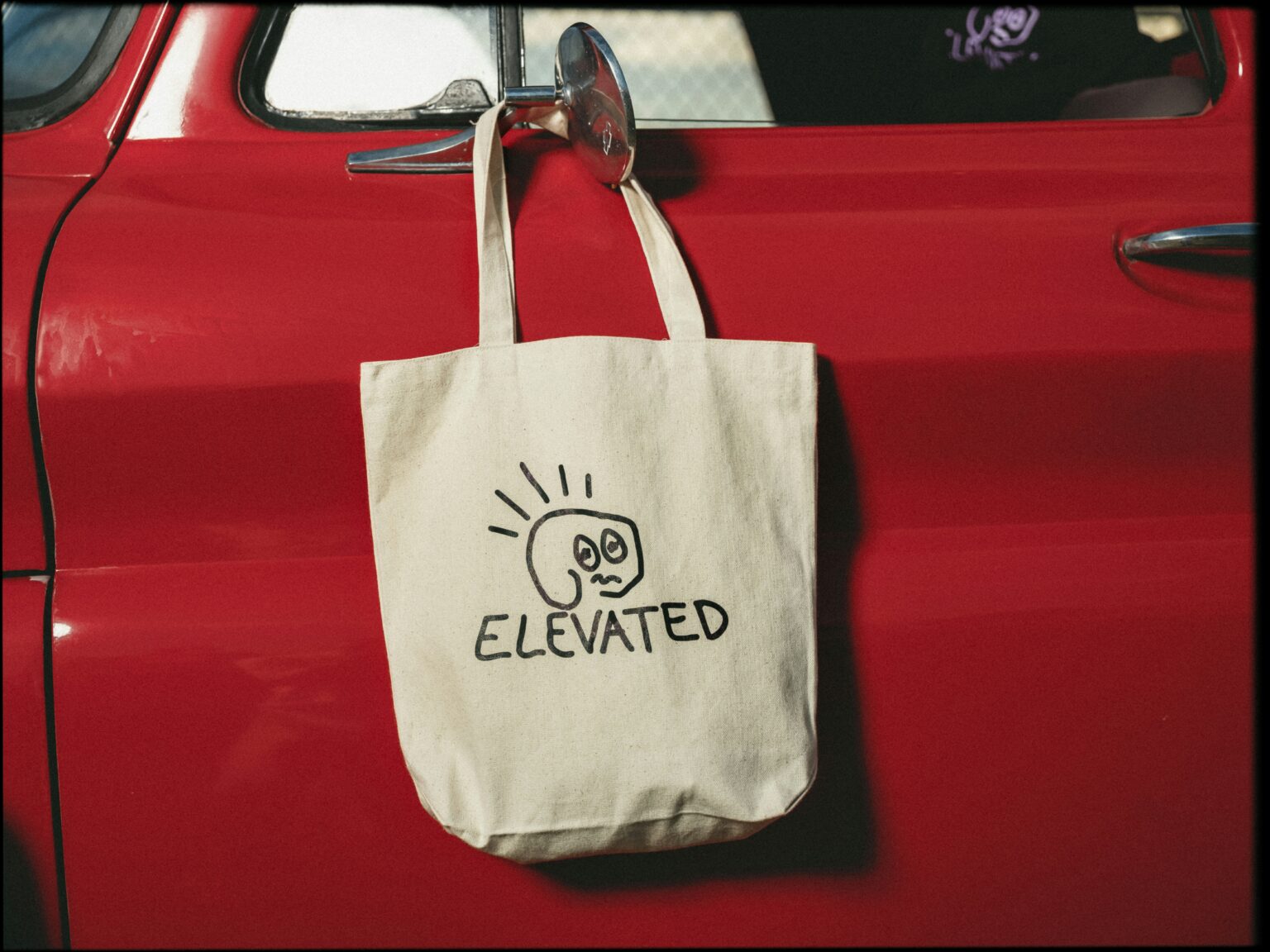 Canvas travel tote hanging on a vintage red car door mirror