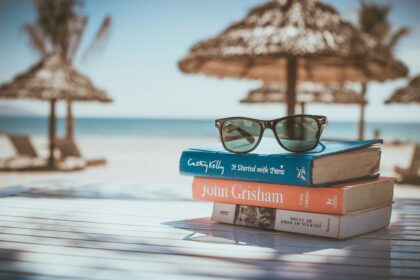 A stack of books and sunglasses on a beach table, the kind of scene readers picture when asking what is a travel blog