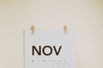 Best places to travel in November shown by a November calendar beside a woven travel bag and sunglasses