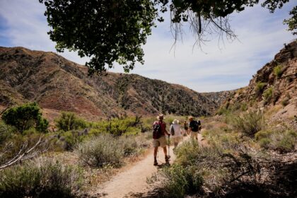 Best hiking trails in the US shown by a hiker on a mountain ridge trail with wide valley views