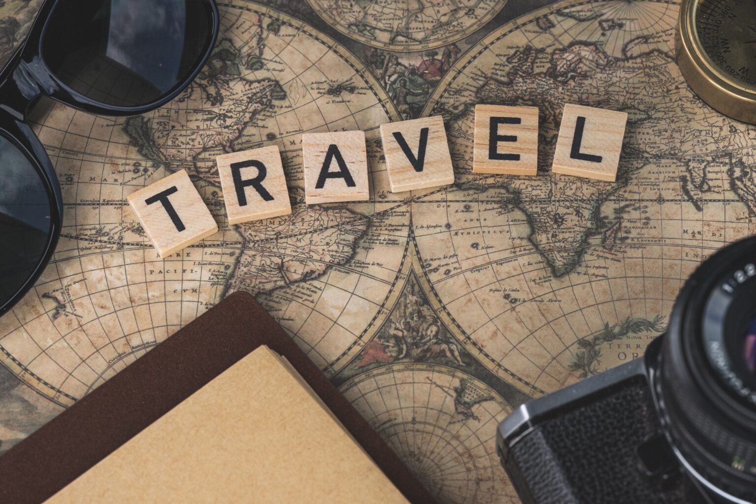 Where to travel in summer shown by a sunny coastline with clear water and mountains behind