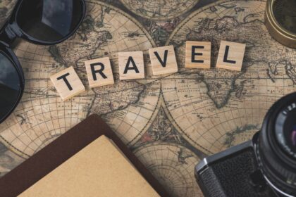 Where to travel in summer shown by a sunny coastline with clear water and mountains behind