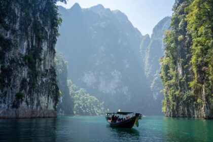 Tropical limestone cliffs and a boat on calm water for a travel destination.