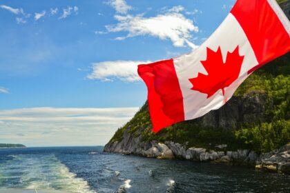 Canadian flag flying from a boat near a rocky coastal cliff