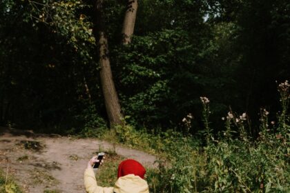 Toddler hiking boots shown on a small child walking on a soft woodland path