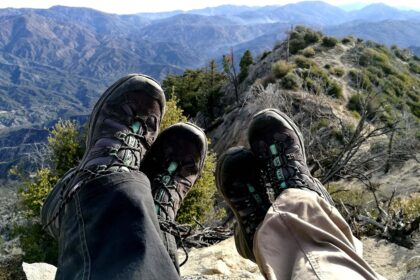 Waterproof hiking boots shown on a wet muddy trail with water beading on the leather