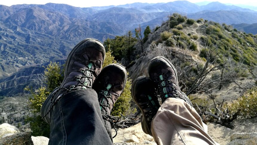 Waterproof hiking boots shown on a wet muddy trail with water beading on the leather