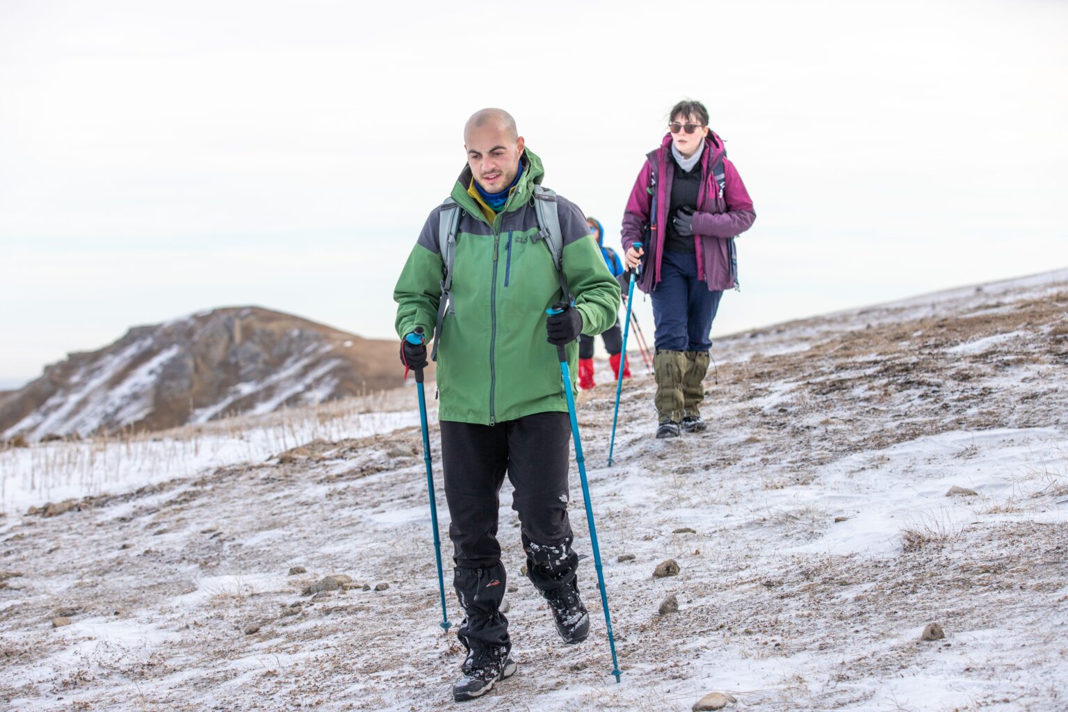 What to wear when hiking shown by a hiker in layered clothing with a pack on a mountain trail