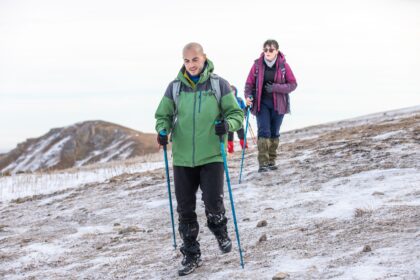 What to wear when hiking shown by a hiker in layered clothing with a pack on a mountain trail