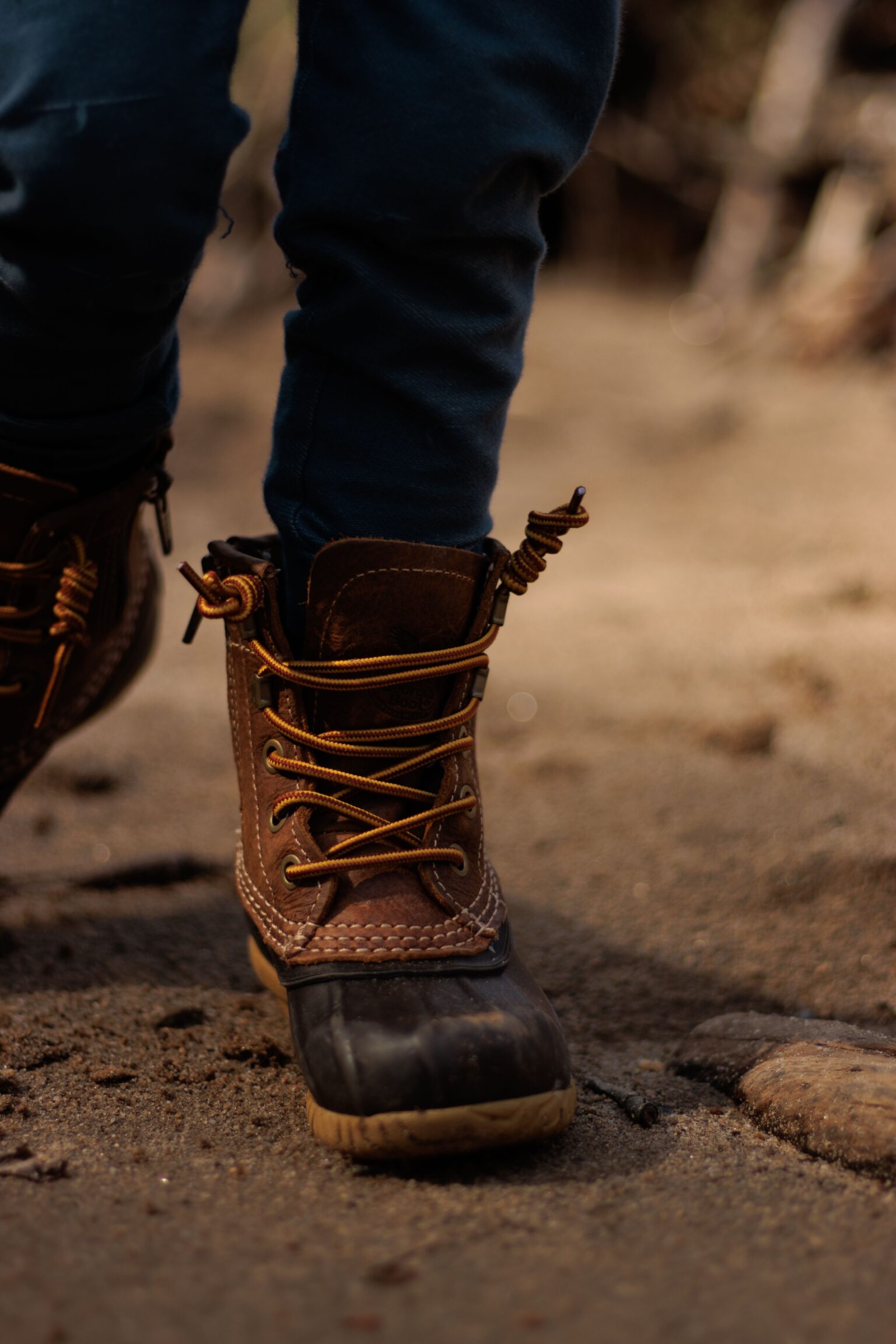 Kids hiking boots shown on a child standing on a rocky woodland trail