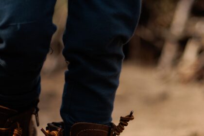 Kids hiking boots shown on a child standing on a rocky woodland trail